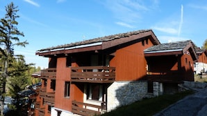 Een houten chalets met een stenen fundering, houten balkons en een schuin dak.