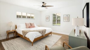Une chambre à coucher comprenant un lit, un ventilateur de plafond, une table de chevet, un bureau et une chaise.
