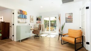 Une pièce spacieuse dotée d’un plancher en bois, d’un bureau avec une chaise, d’une bibliothèque et d’un coin repas avec une table et des chaises.