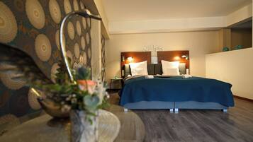 Een hotelkamer met een bed, nachtkastje, lamp en decoratieve wand.