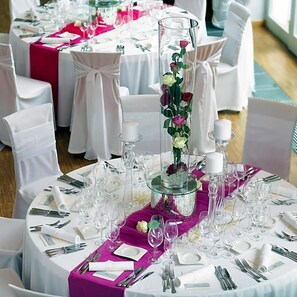 A round dining table with white tablecloths, pink centerpieces, and white chairs. - Zum Schwanen (Osthofen)