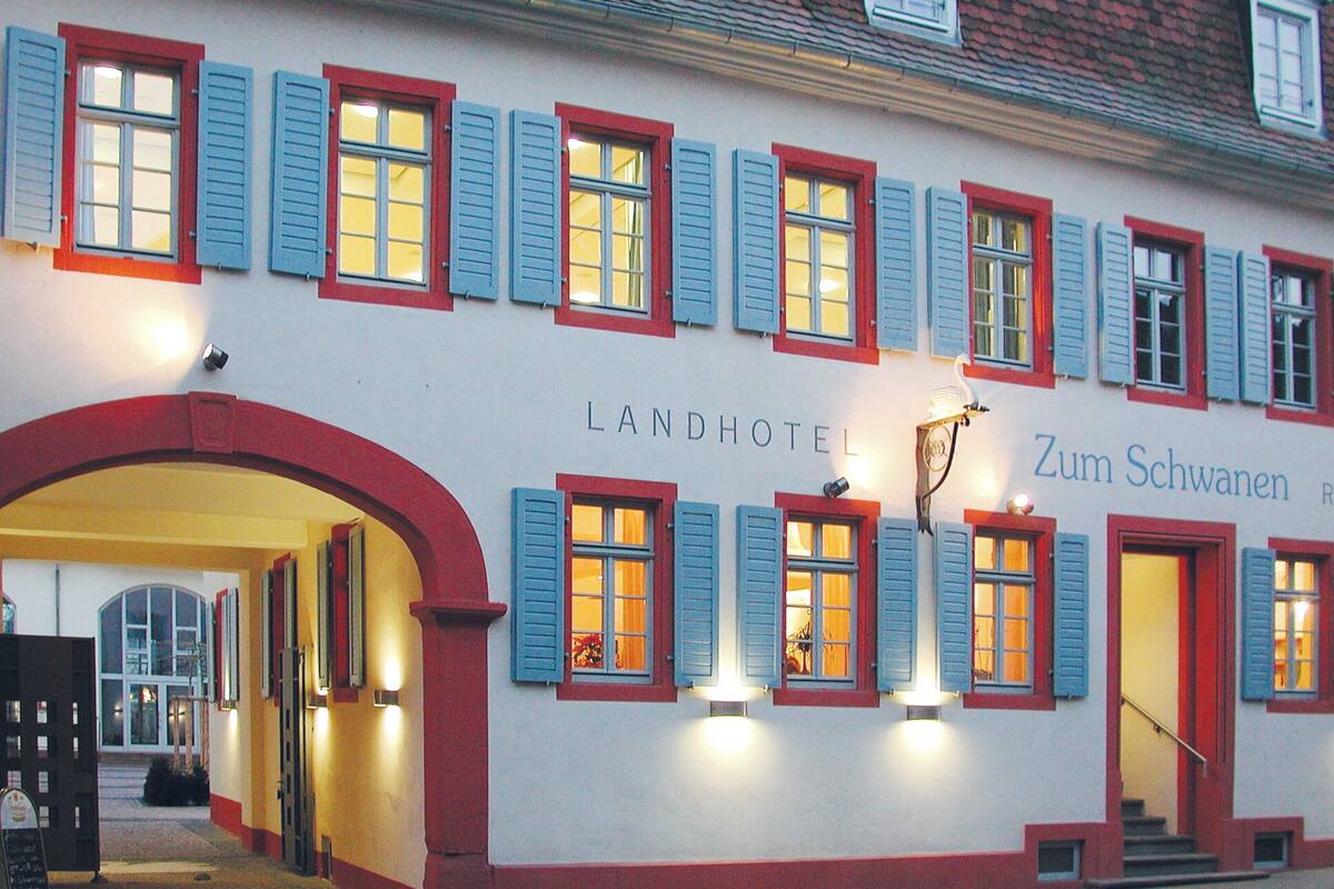 Ein Hotel mit weißer Fassade, roter Verzierung und blauen Fensterläden.