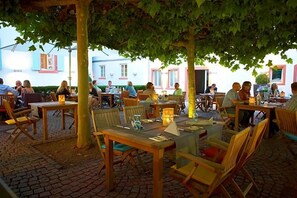 An outdoor café with wooden tables and chairs, surrounded by trees. - Zum Schwanen (Osthofen)