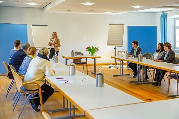 A conference room with a long table, chairs, a whiteboard, and a presentation screen. - Zum Schwanen (Osthofen)
