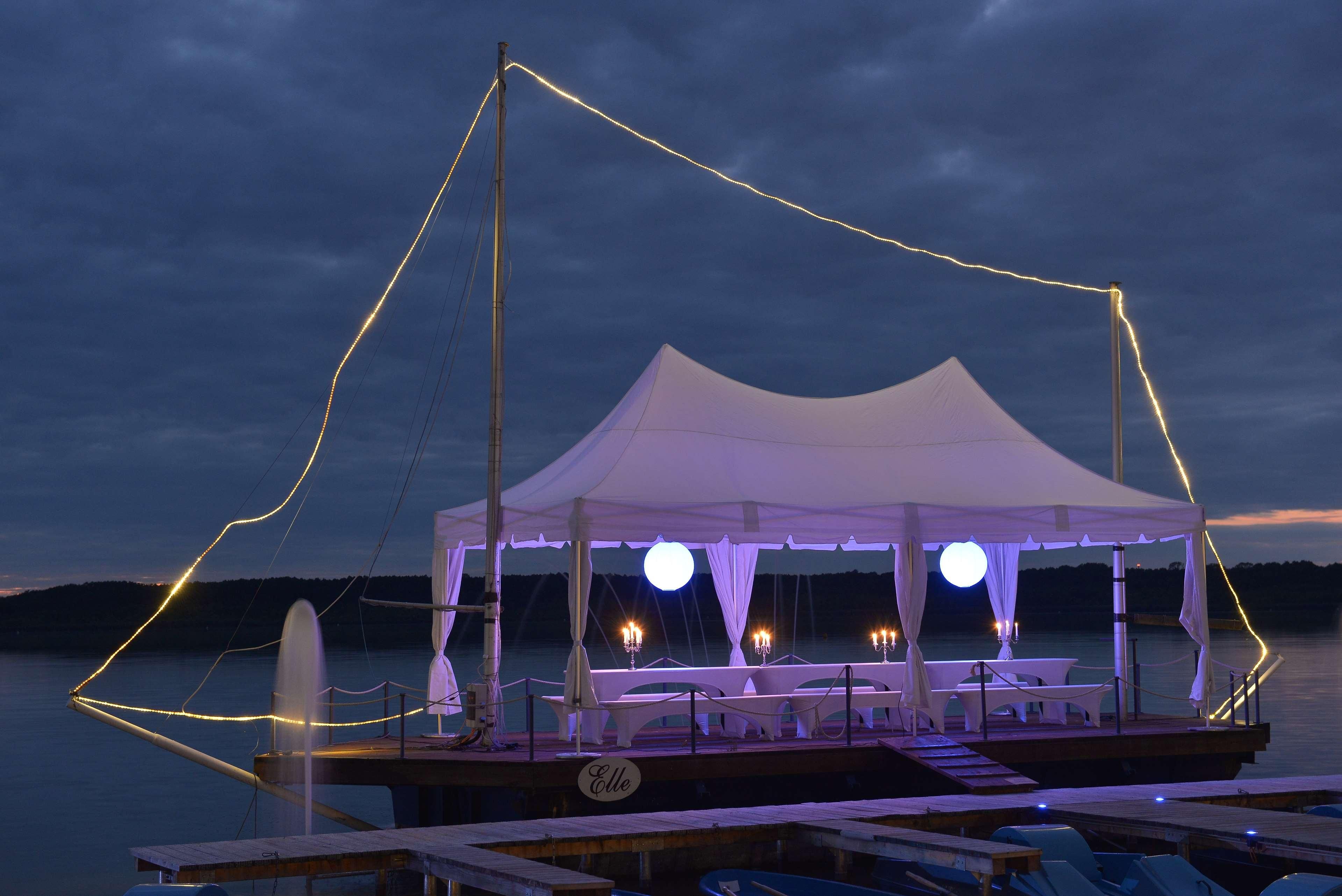 A boat with a covered dining area, white canopies, and tables with candles.
