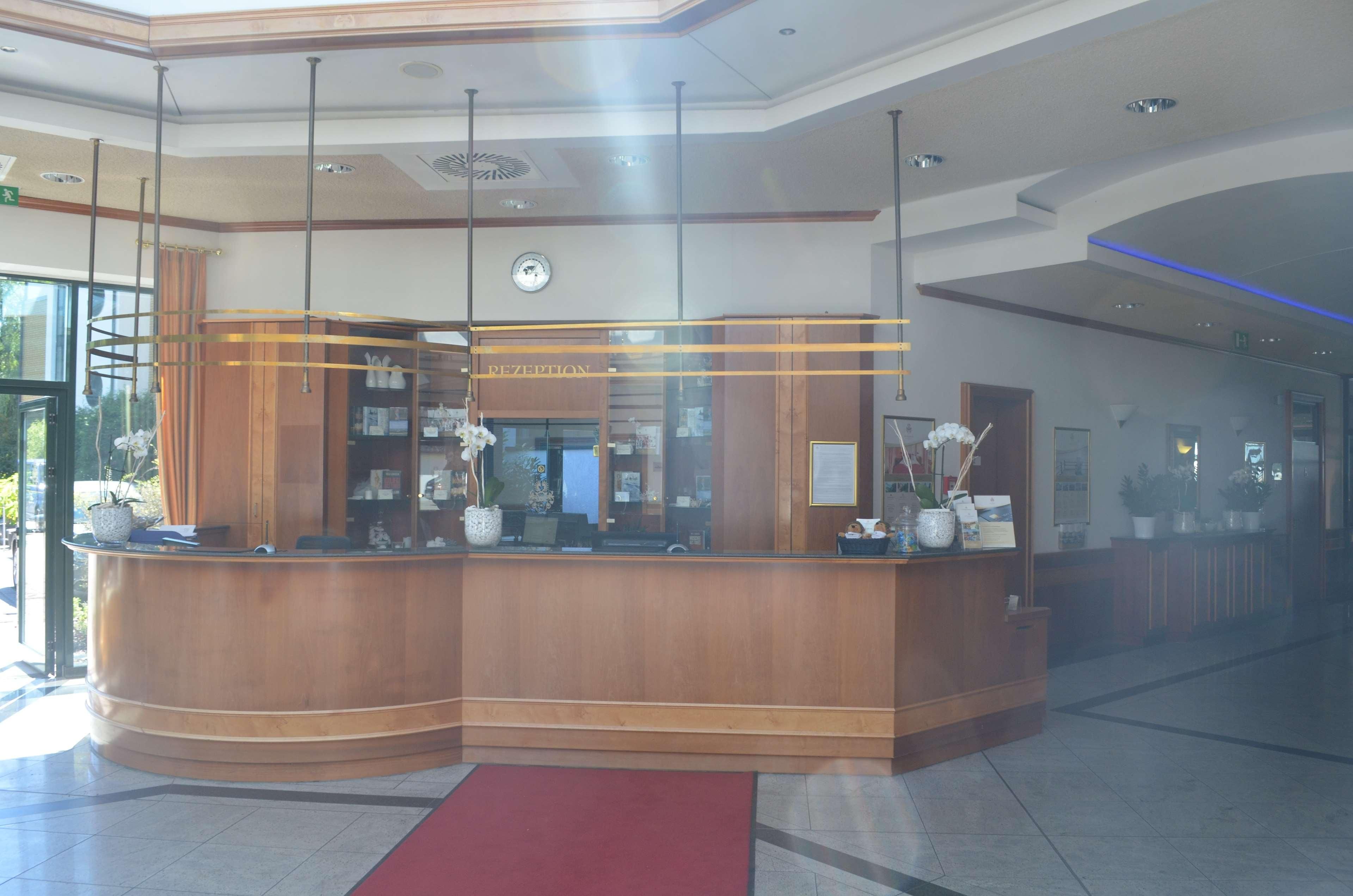 A reception area with a curved wooden counter, a clock, and a red carpet.