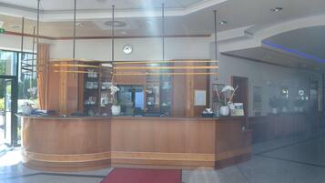 A reception area with a curved wooden counter, a clock, and a red carpet.