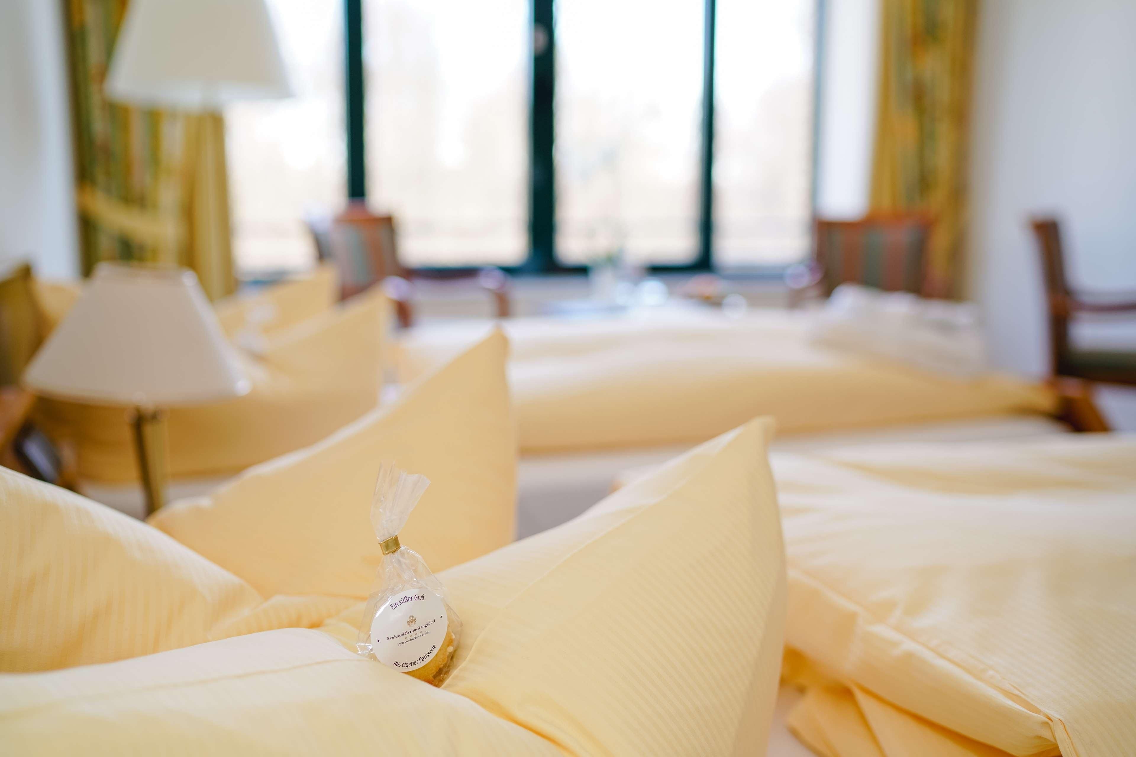 A hotel room with multiple beds, each with a pillow and a small gift bag.