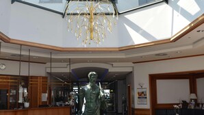A spacious atrium with a glass ceiling, a central statue, and a chandelier. - TOP Countryline Seebad Casino (Rangsdorf)