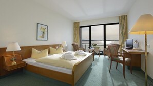 A hotel room with a bed, desk, chair, and a view of the outdoors. - TOP Countryline Seebad Casino (Rangsdorf)