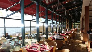 An outdoor dining area with tables set for two, overlooking a body of water. - TOP Countryline Seebad Casino (Rangsdorf)