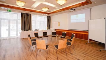 A conference room with a round table, chairs, a projector screen, and a whiteboard.