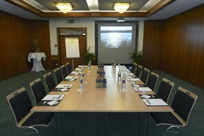 A conference room with a long table, chairs, a projector screen, and a whiteboard.