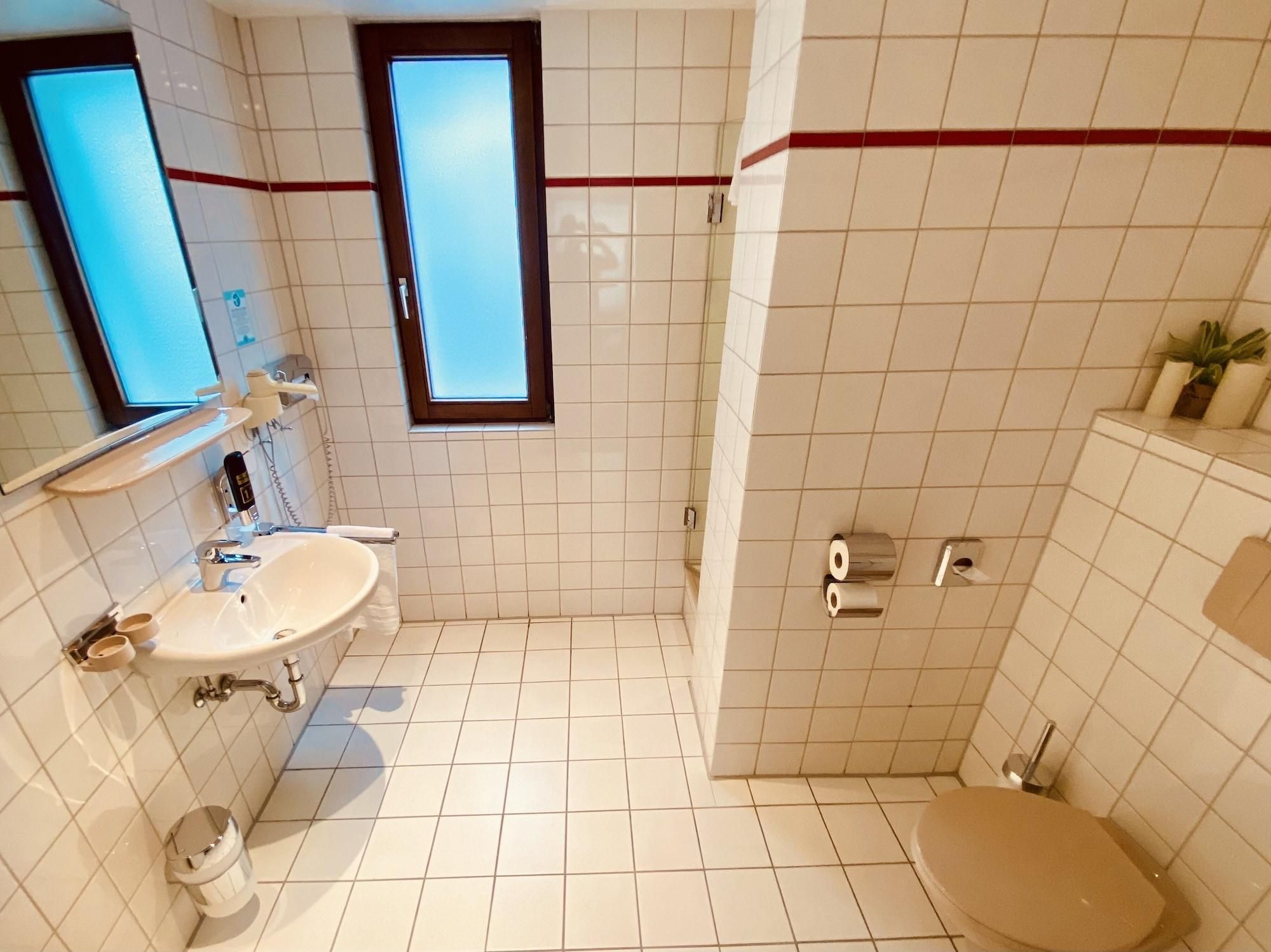 Ein Badezimmer mit Waschbecken, Spiegel, Toilette und Dusche.
