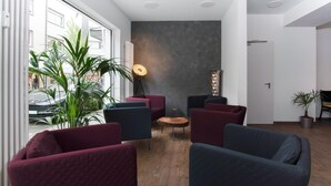 Una sala de estar moderna con un gran ventanal, varios sofás, una mesa redonda y una lámpara.