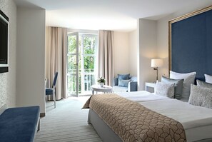 Een hotelkamer met een groot bed, een zithoek met een tafel en stoelen, en een uitzicht door een glazen deur.