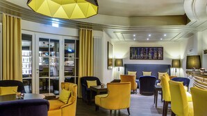 Un hall d’hôtel moderne doté d’un espace salon, d’un bar et d’une bibliothèque.