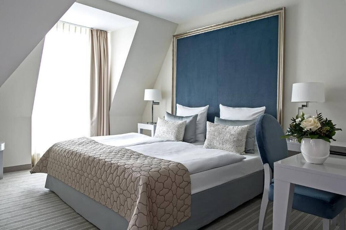 A modern hotel room with a large bed, a desk, and a window with curtains.