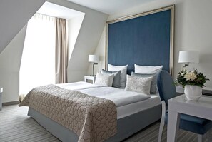 Een moderne hotelkamer met een groot bed, een bureau en een raam met gordijnen.