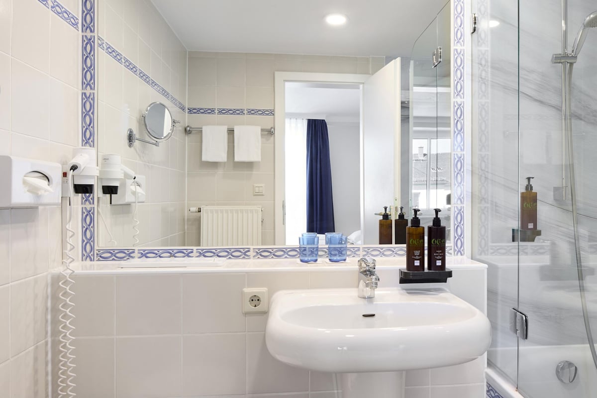 A bathroom with a sink, mirror, towel rack, and shower.