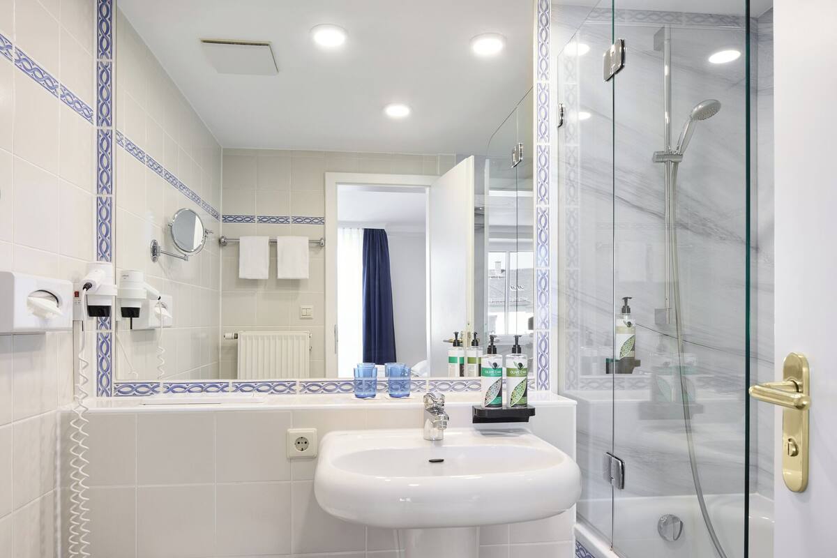 A modern bathroom with a glass-enclosed shower, a white sink, and a mirror.