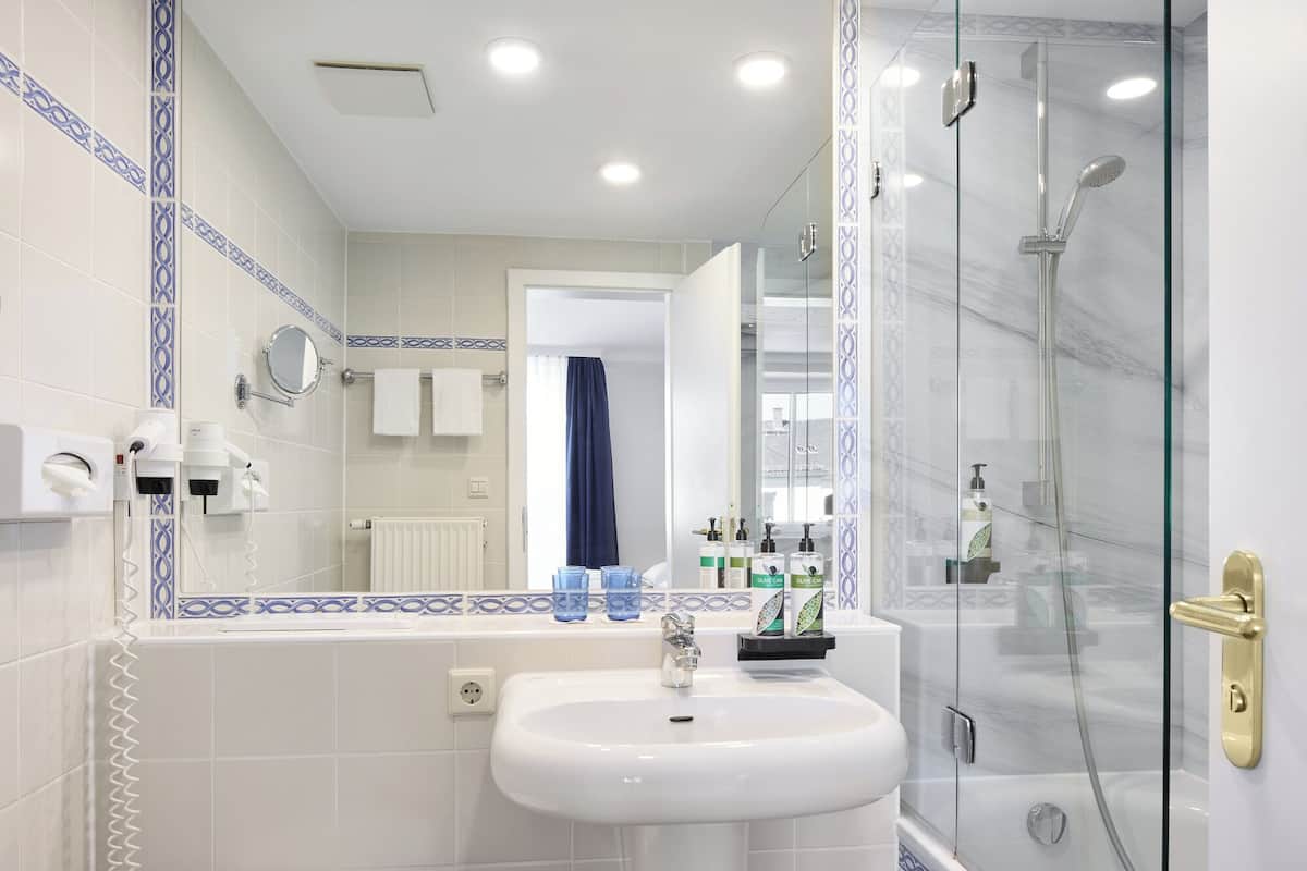 A modern bathroom with a glass-enclosed shower, a white sink, and a mirror.