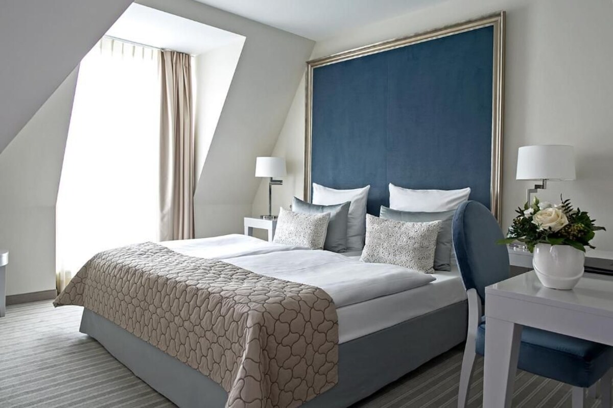 Une chambre d’hôtel moderne avec un grand lit, un bureau et une fenêtre avec des rideaux.