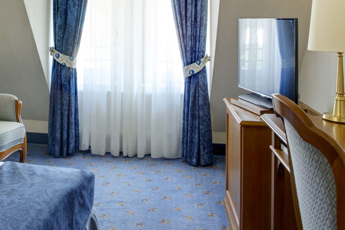 Une chambre d’hôtel avec un lit, une chaise, un bureau avec une lampe et un téléviseur.