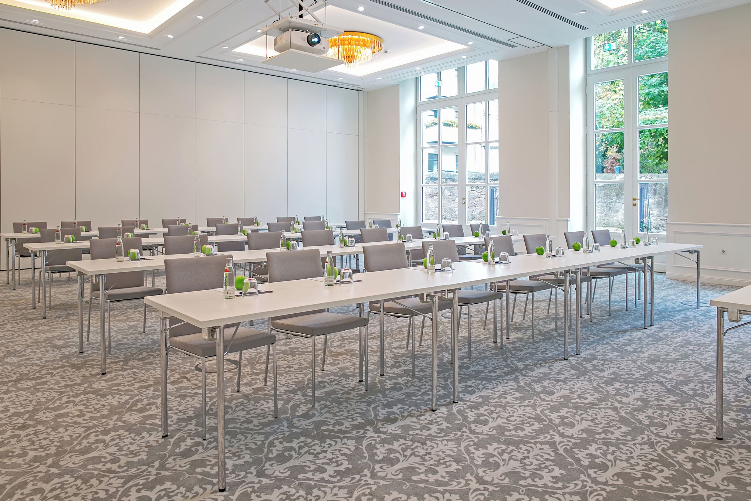 Une salle de conférence équipée de longues tables, de chaises et d’un écran de projection.