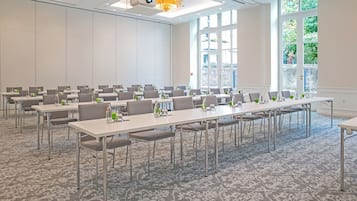 Une salle de conférence équipée de longues tables, de chaises et d’un écran de projection.