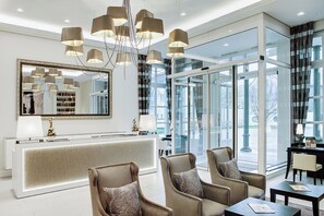 A modern hotel lobby with a reception desk, seating area, large mirror, and contemporary lighting. - Dorint Parkhotel Meissen (Nossen)