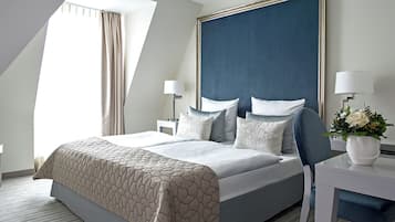 A modern hotel room with a large bed, a nightstand, a desk, and a window with curtains.