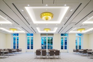 A spacious conference room with a high ceiling, recessed lighting, and chandeliers. - Dorint Parkhotel Meissen (Nossen)