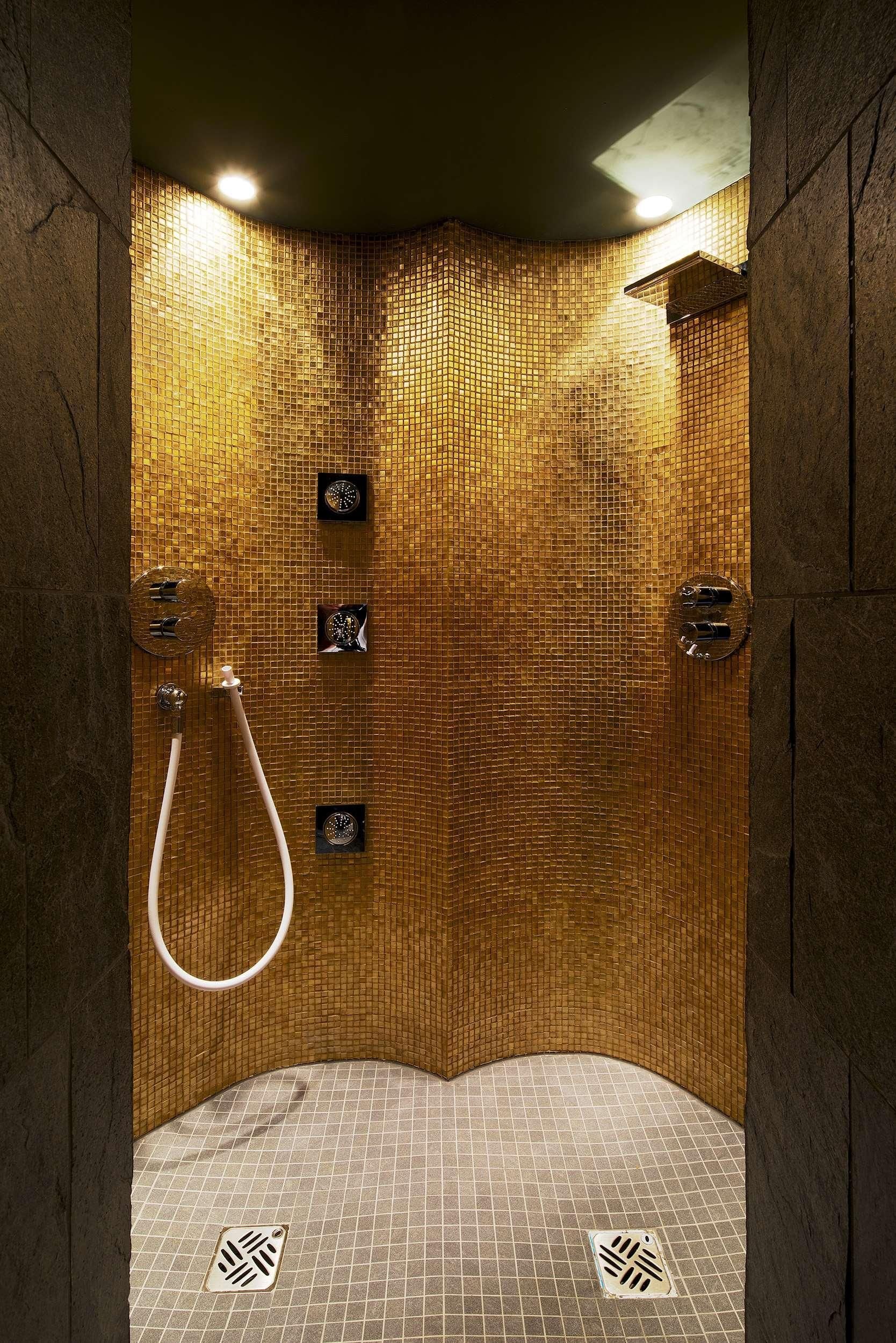 Une douche avec un mur carrelé et un drain.