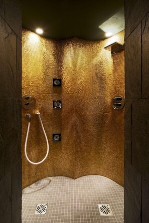 Une douche avec un mur carrelé et un drain.