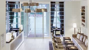 Una hall d'albergo con reception, area relax e una libreria.