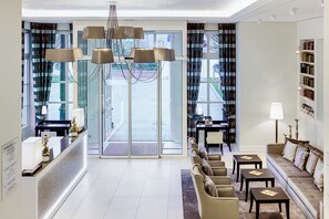 A hotel lobby with a reception desk, seating area, and a bookshelf. - Dorint Parkhotel Meissen (Nossen)