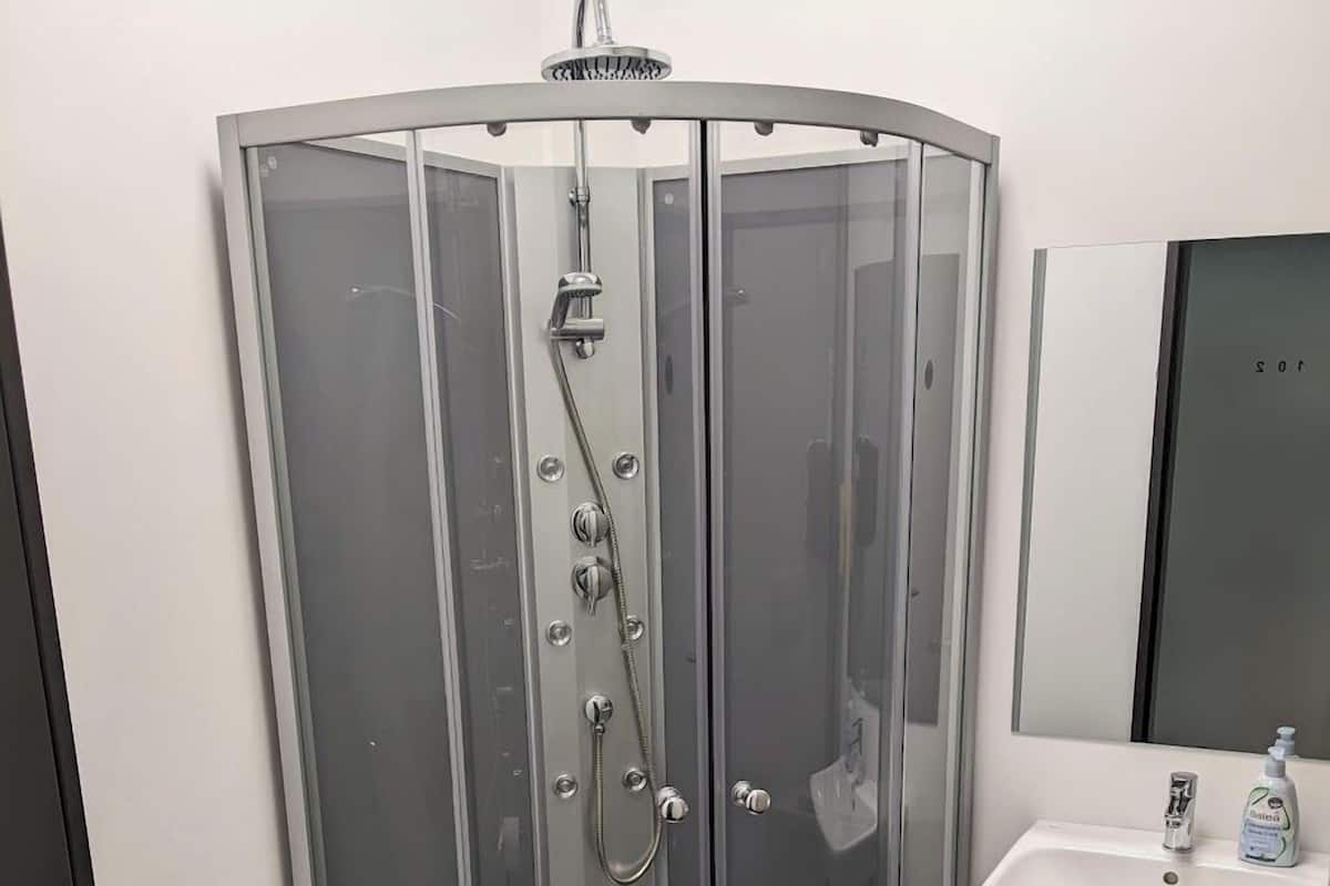 Un baño moderno con ducha de vidrio, lavamanos blanco y retrete.