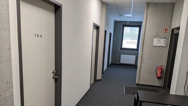 A corridor with doors numbered 104 and 105, a fire extinguisher, and a window with a view of trees. - Business-motel mit Xl-parking (Heimsheim)