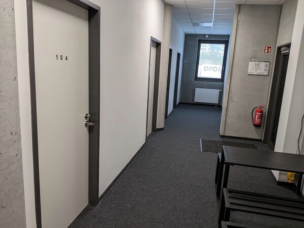 A corridor with doors numbered 104 and 105, a fire extinguisher, and a window with a view of trees. - Business-motel mit Xl-parking (Heimsheim)