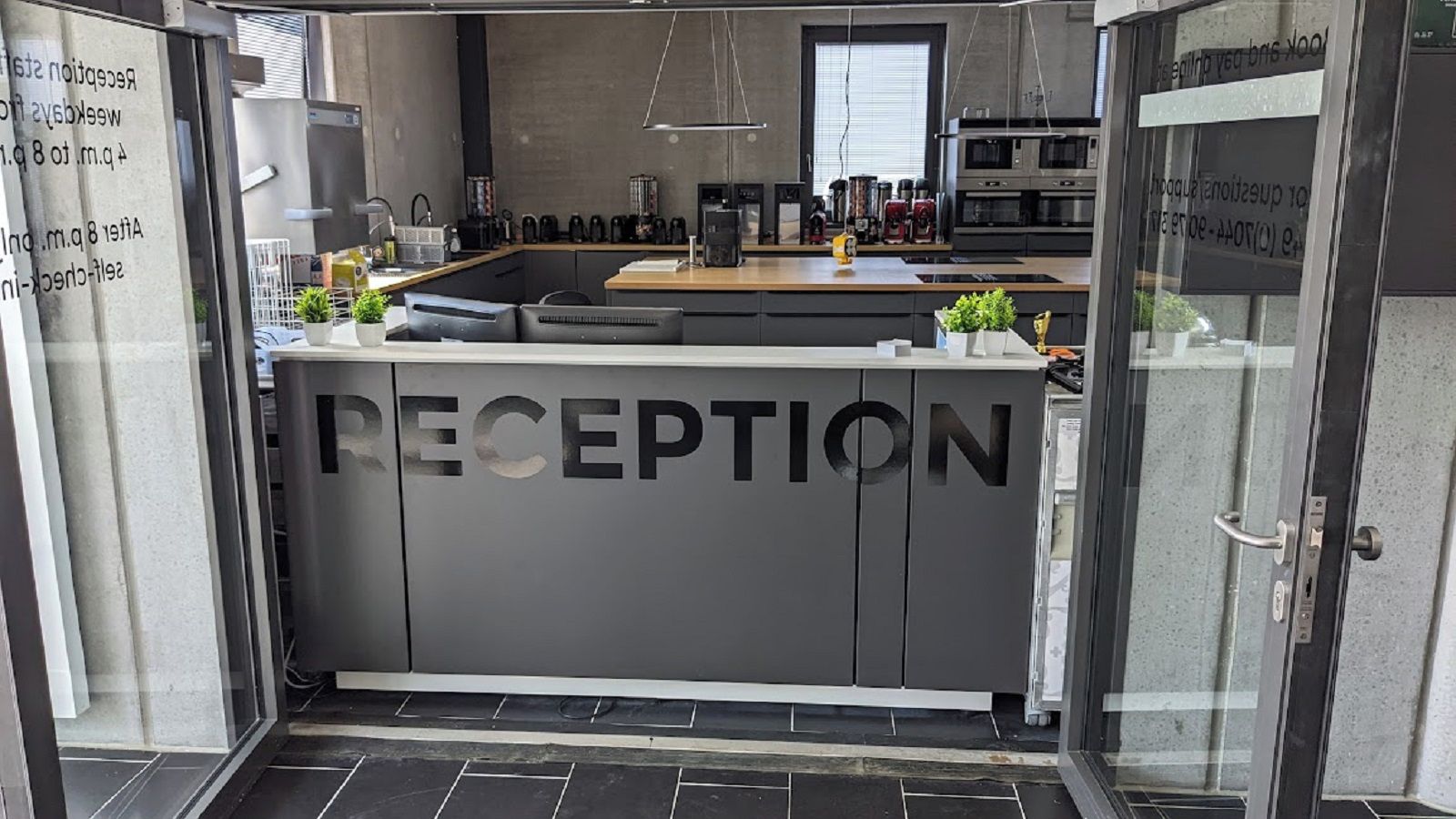 A reception area with a grey reception desk, a coffee machine, and a microwave.