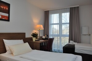 A hotel room with two beds, a desk with a lamp, a chair, and a window with curtains. - Best Western Hotel Erlangen (Erlangen)