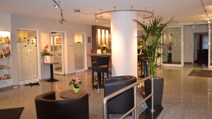A modern hotel lobby with a reception desk, seating area, and a large potted plant. - Best Western Hotel Erlangen (Erlangen)
