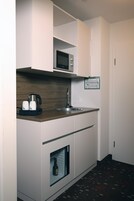 A compact kitchenette with a microwave, kettle, and coffee maker, a sink, and a wine cooler.