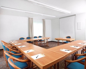 A conference room with a long table, blue chairs, and a large window with curtains. - Best Western Hotel Erlangen (Erlangen)