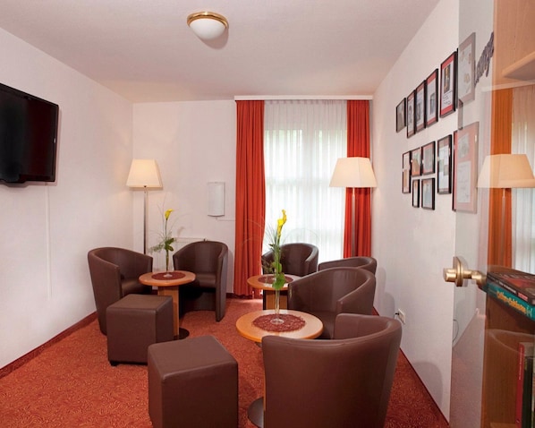 A hotel room with a flat-screen TV, two armchairs, a sofa, a small round table, and a coffee table. - Best Western Hotel Erlangen (Erlangen)