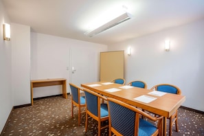 A conference room with a long wooden table, blue upholstered chairs, a small wooden bench, and a whiteboard on the wall. - Best Western Hotel Erlangen (Erlangen)
