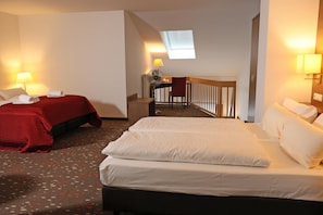 A hotel room with two beds, a desk with a chair, a small table, a fan, and a window with blinds. - Best Western Hotel Erlangen (Erlangen)