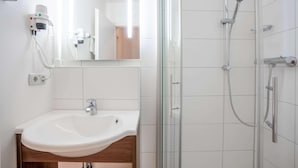 A bathroom with a white sink, a glass shower enclosure, and a hairdryer mounted on the wall. - Best Western Hotel Erlangen (Erlangen)