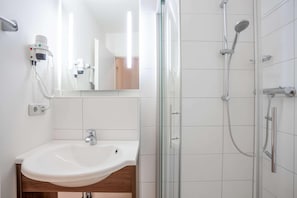 A bathroom with a white sink, a glass shower enclosure, and a hairdryer mounted on the wall. - Best Western Hotel Erlangen (Erlangen)